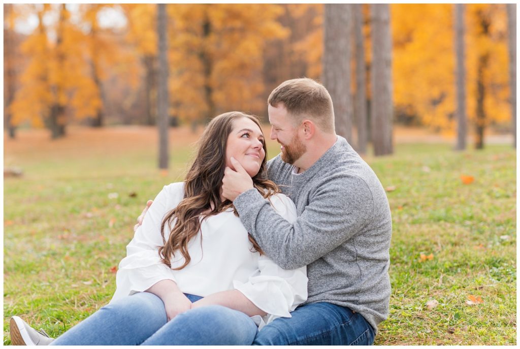 engaged couple sitting in the grass at Norwalk Reservoir in Ohio