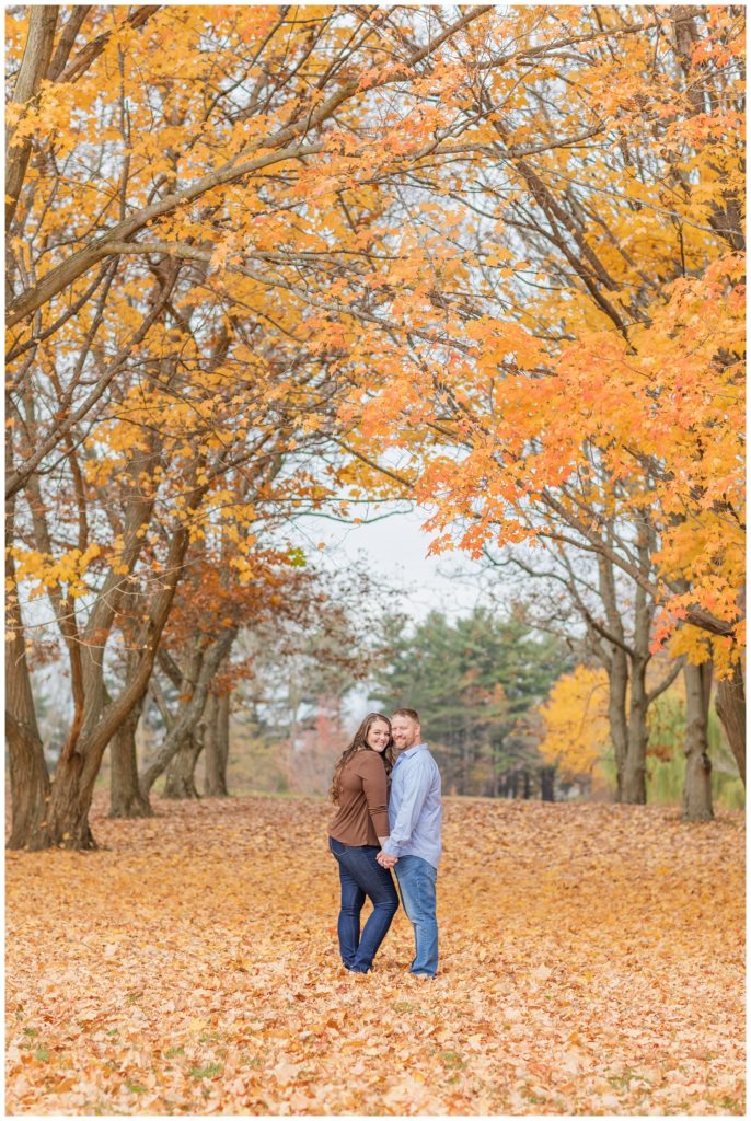 couple posing together on yellow and orange fall leaves in Ohio