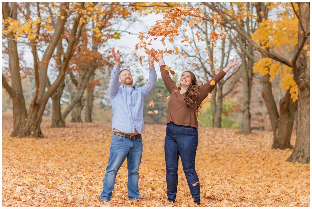 couple throwing up leaves at fall engagement session in Ohio