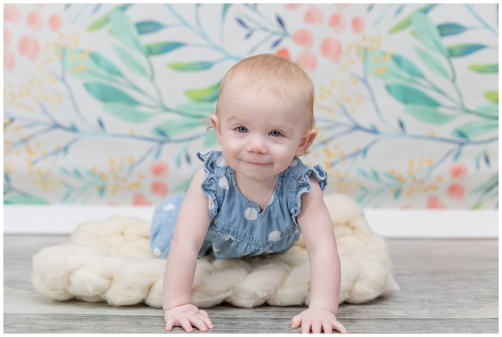 one year old girl crawling on a white blanket at photo session
