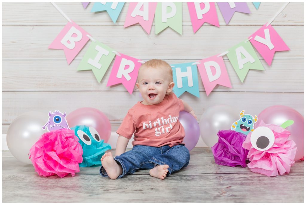 one year old birthday girl wearing a pink shirt and jeans