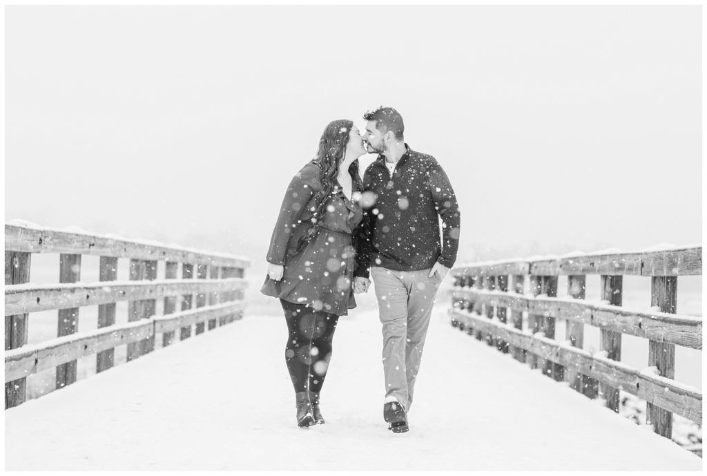 couple walking and kissing with falling snow at Norwalk Reservoir