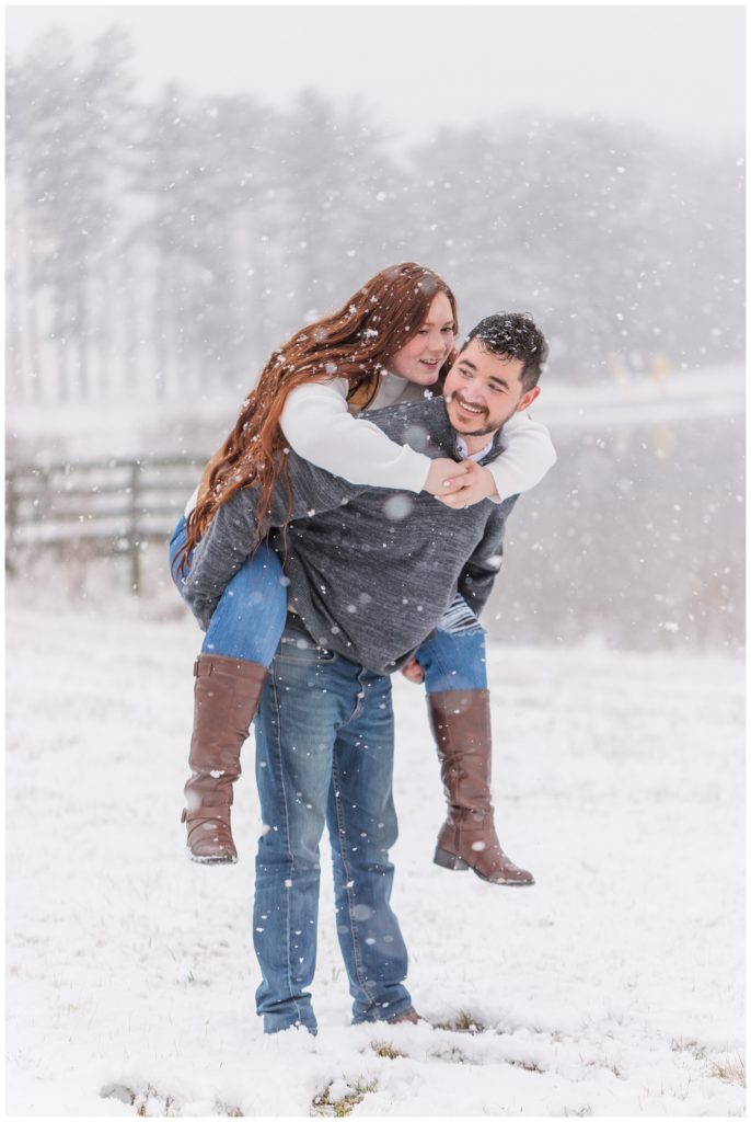 engaged couple piggybacking in the snow at Norwalk Reservoir