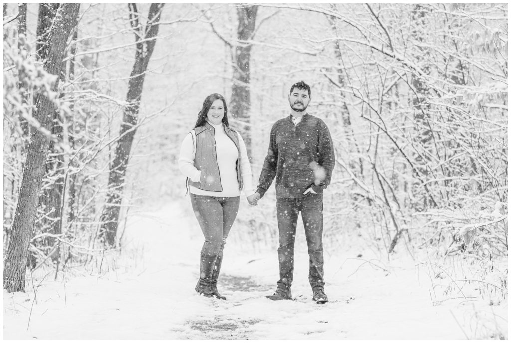 couple standing in front of trees in the snow in Norwalk, Ohio engagement