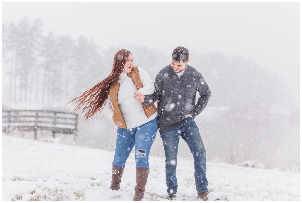 couple laughing at snowy engagement session at Norwalk Reservoir
