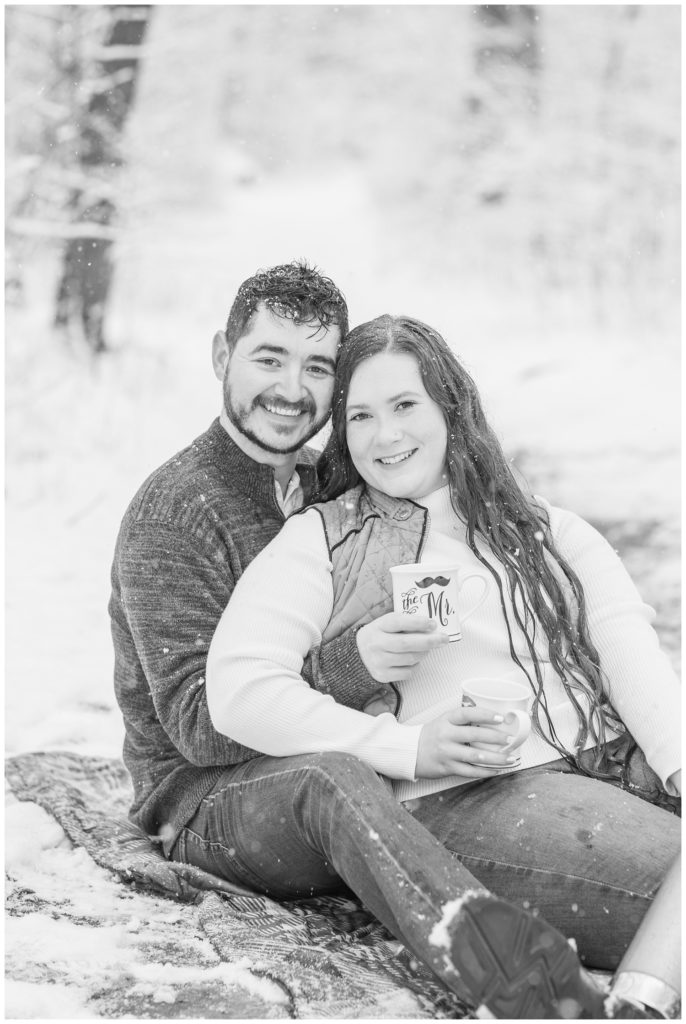 engaged couple holding coffee mugs in the snow at winter photo session in Ohio