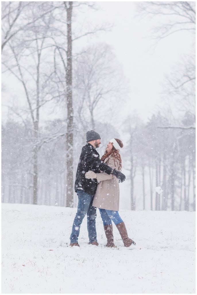couple hugging in the snow at Norwalk Reservoir engagement session