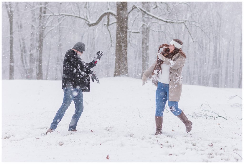 couple having a snowball fight at Ohio winter engagement session