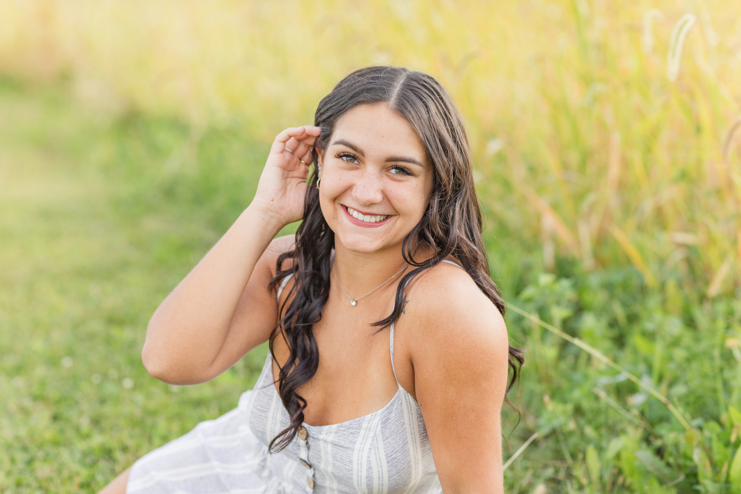 senior girl sitting in a field at Creek Bend Farm