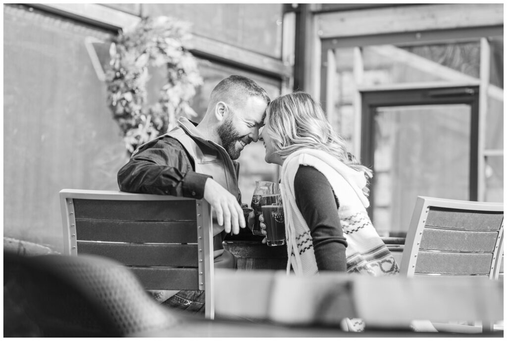 engaged couple touching foreheads at brewery engagement session