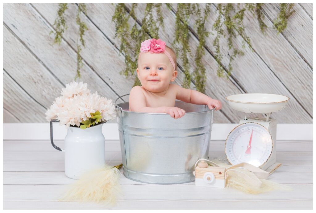 one year old girl sitting in a metal bucket for photo session