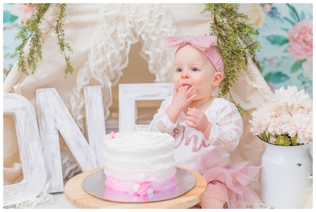 little girl eating a pink and white cake at photo session