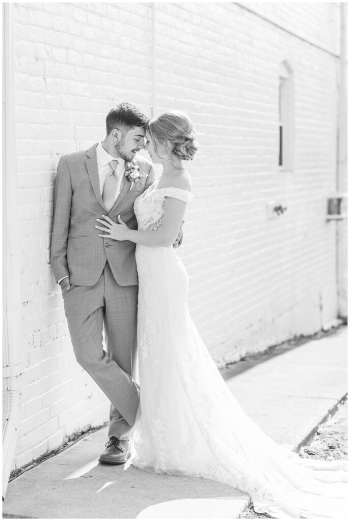 bride and groom standing against a brick wall in downtown Tiffin