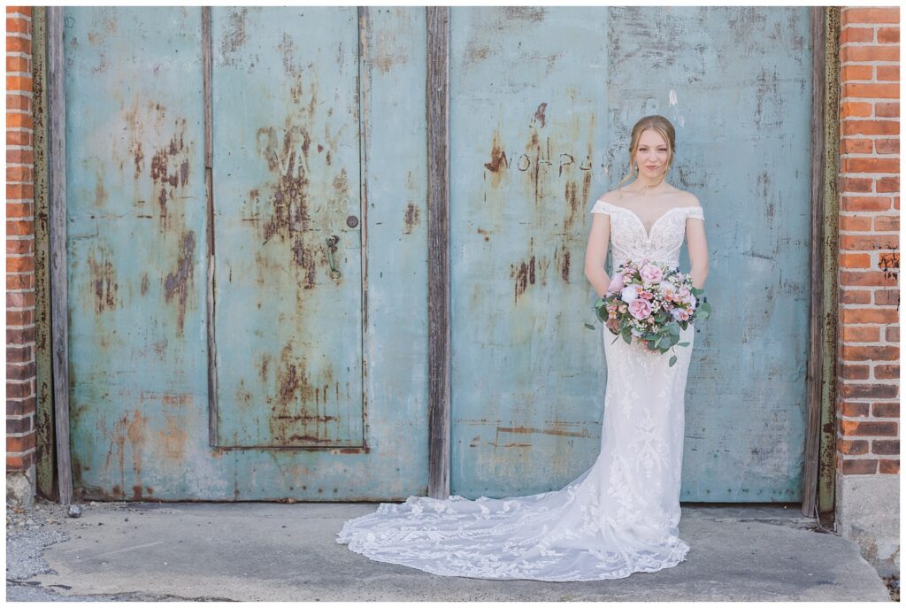 bride holding bouquet standing next to a set of blue doors 