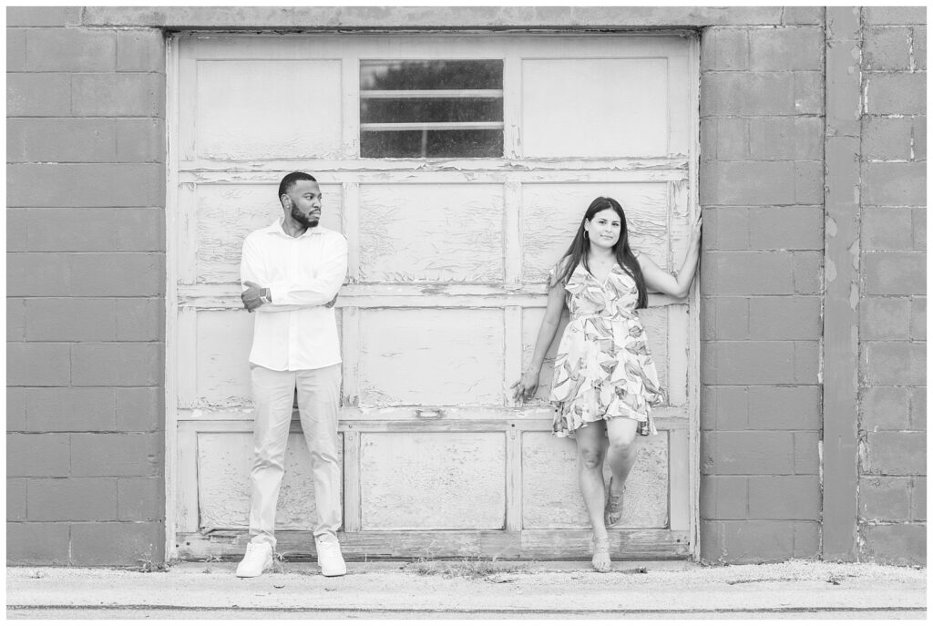 couple standing against a garage door and brick wall