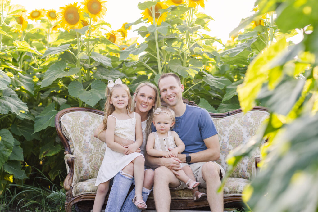 family sitting on a couch in a sunflower field