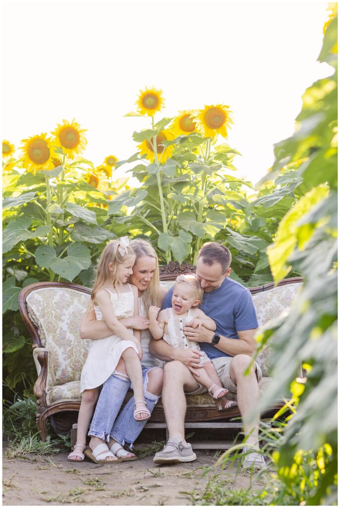family laughing while sitting on a couch in a sunflower field in Ohio