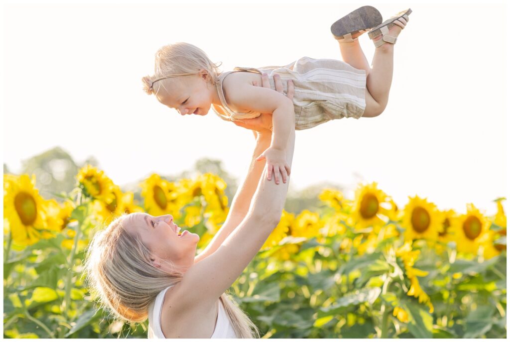 mom holding her daughter up in the air at Liindsey, Ohio sunflower farm