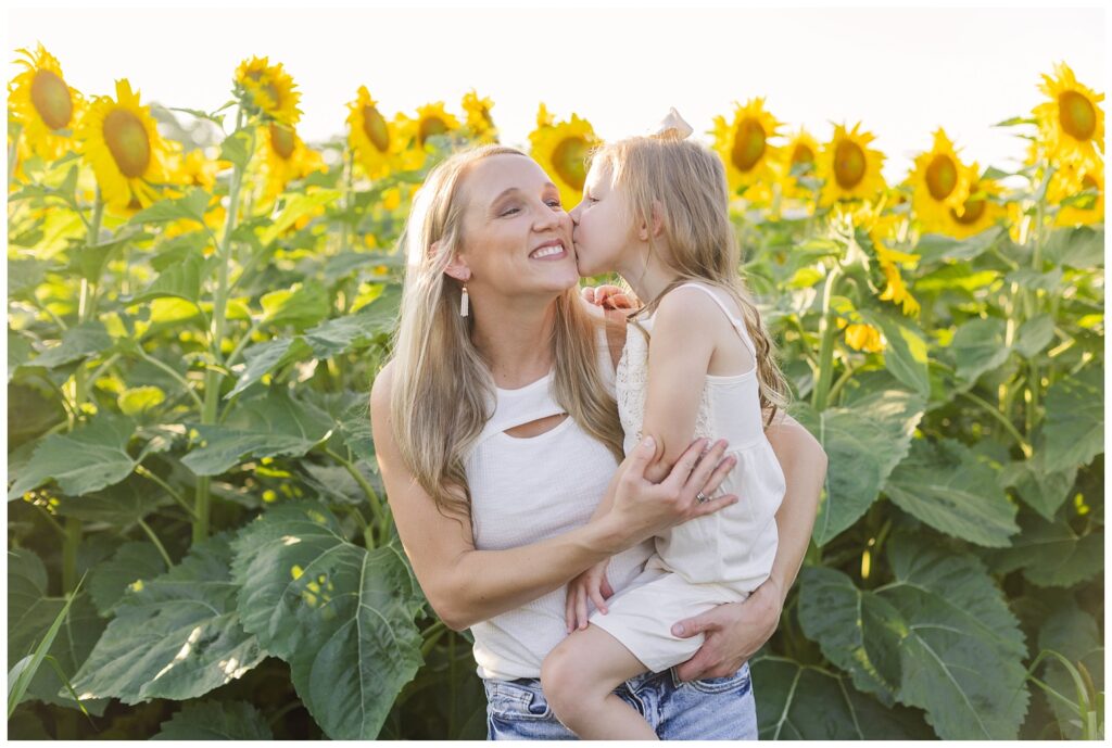 mom holding her daughter in front of sunflowers in Ohio