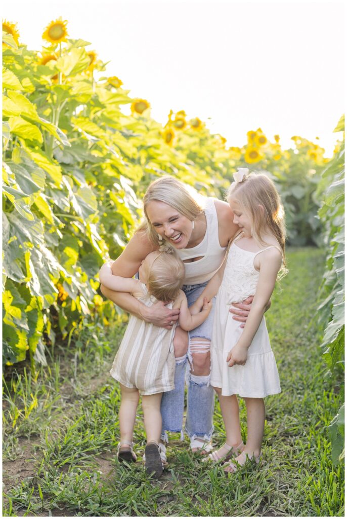 mom hugging her girls in a sunflower field in Ohio