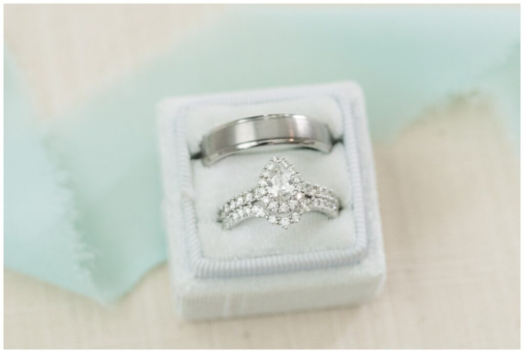 wedding rings sitting in an ivory box on top of mint green ribbon