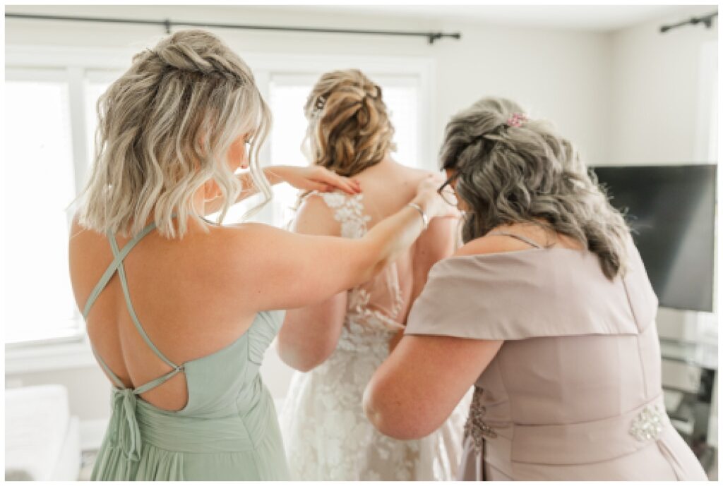 mom and bridal party helping bride get dressed for wedding in Ohio