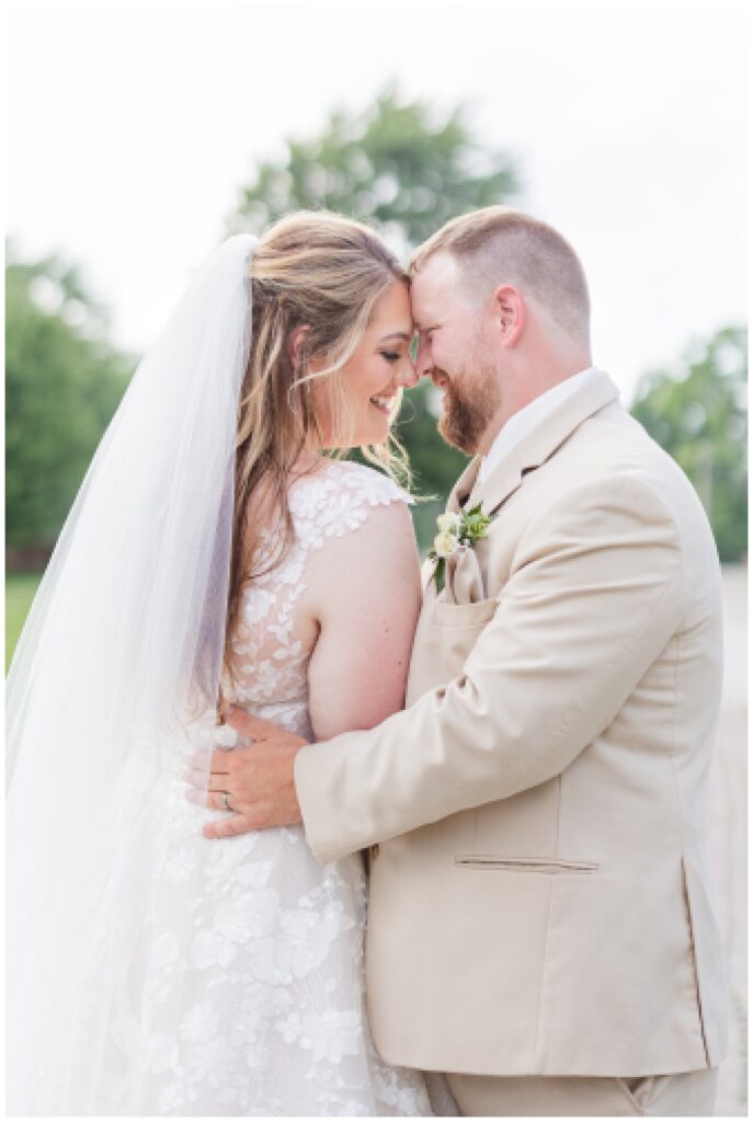bride wearing a lace dress and groom wearing a tan colored suit at wedding