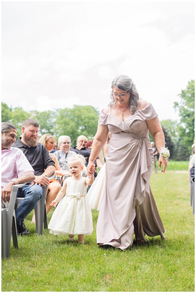 grandmother walking bride and groom's daughter down the aisle
