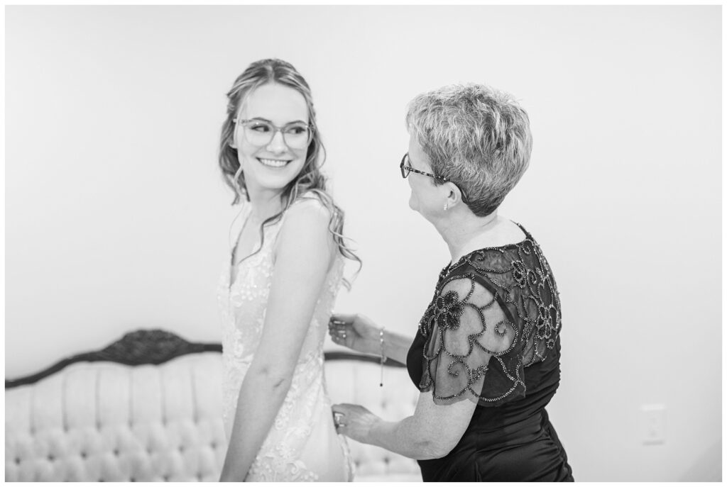 bride's mom zipping up bride's dress while getting ready