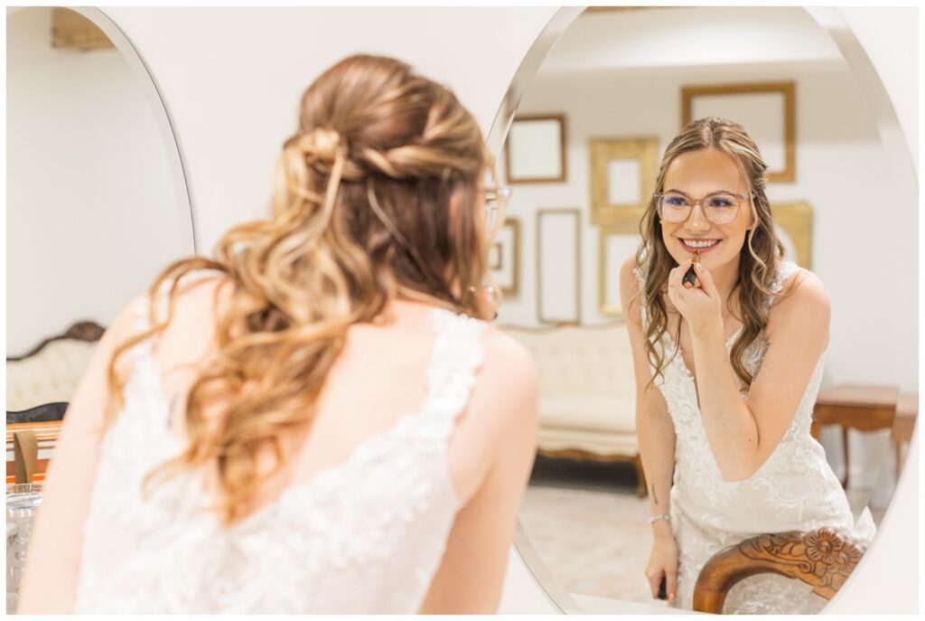 bride putting on lipstick at getting ready suite at Tiffin, Ohio wedding venue