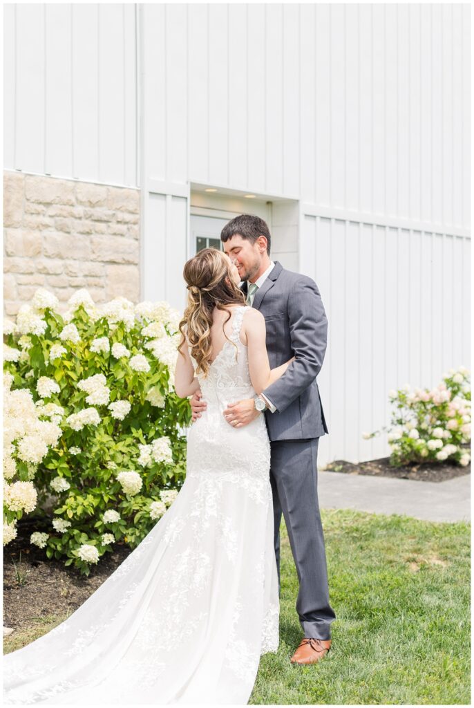 first look with bride and groom outside next to white hydrangeas 