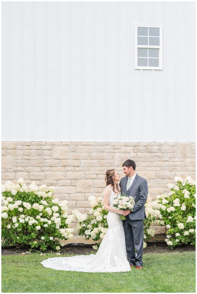 couple posing together outside in front of white hydrangeas in Tiffin, Ohio