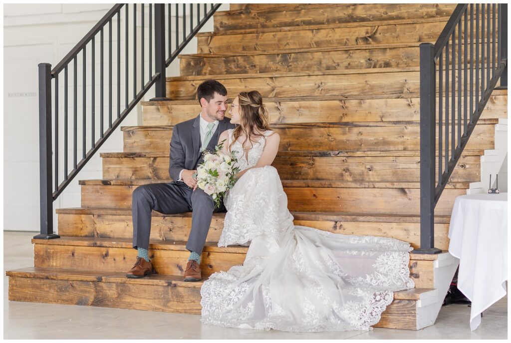 wedding couple sitting on wood stairs at reception hall in Tiffin, Ohio