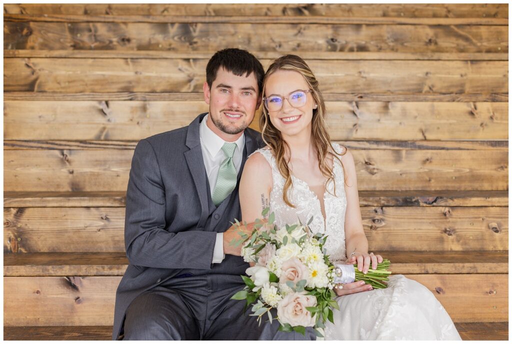wedding couple sitting together on wood stairs at reception venue