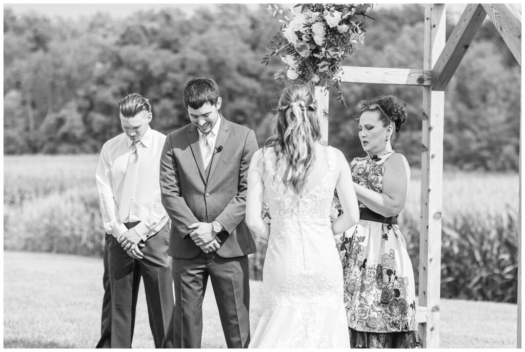 bride and groom praying during ceremony at rustic barn venue