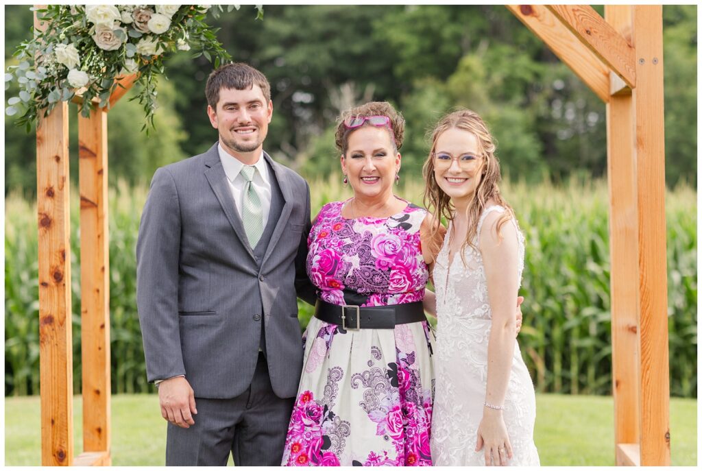 wedding couple posing with officiant at Arlington Acres venue