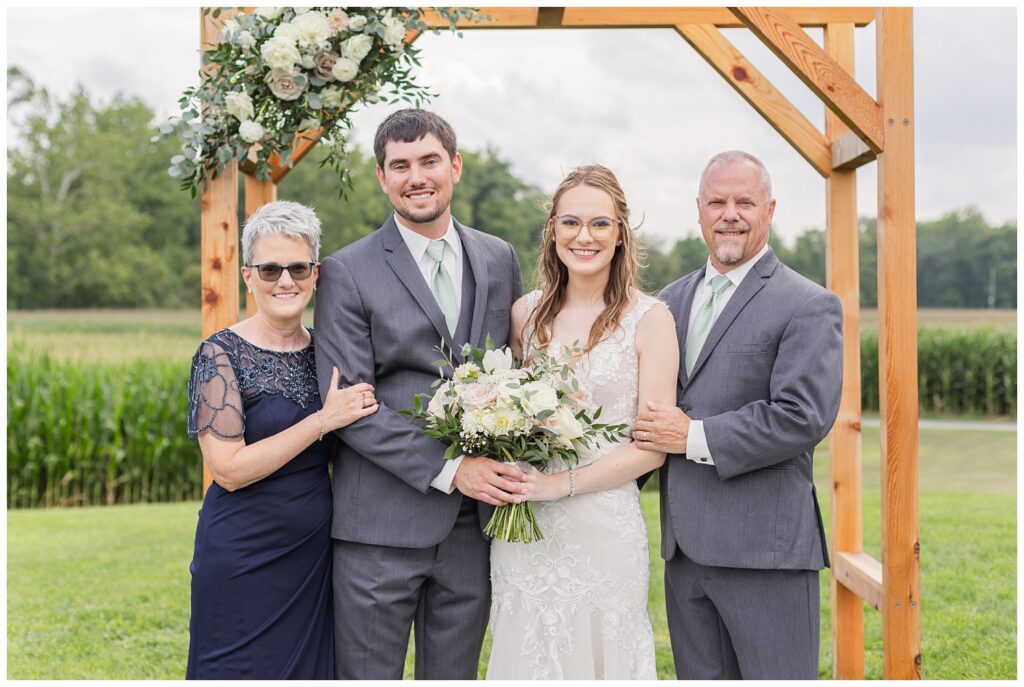 bride and groom posing with parents at summer wedding in Tiffin, Ohio