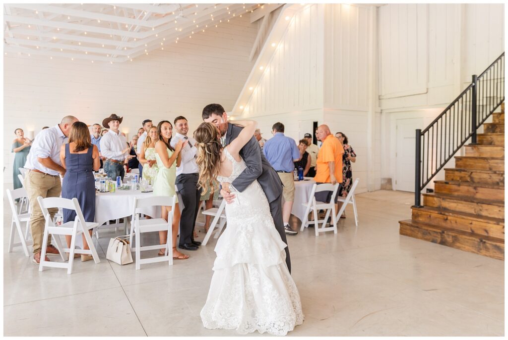 bride and groom share kiss after grand entrance into rustic barn reception