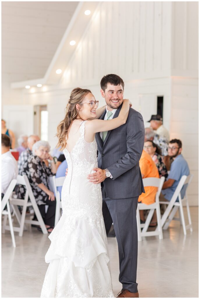 wedding couple smiling at guests during first dance at summer reception