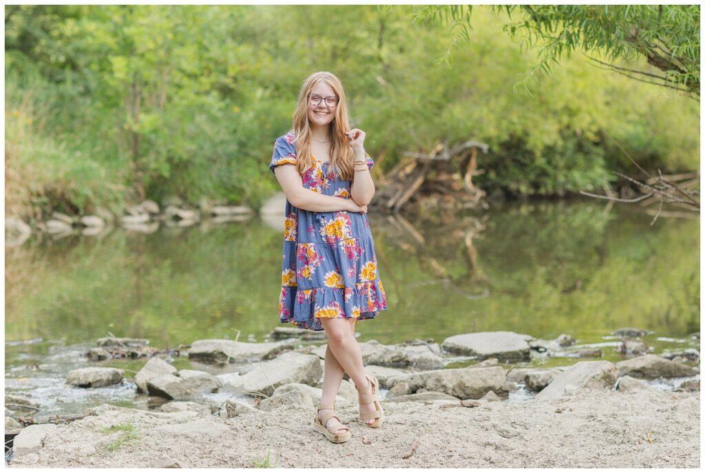 senior standing among rocks in a creek for session at Creek Bend Farms