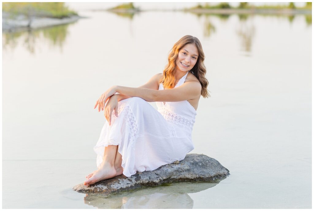 high school senior wearing a white dress and sitting in a rock in northeast Ohio