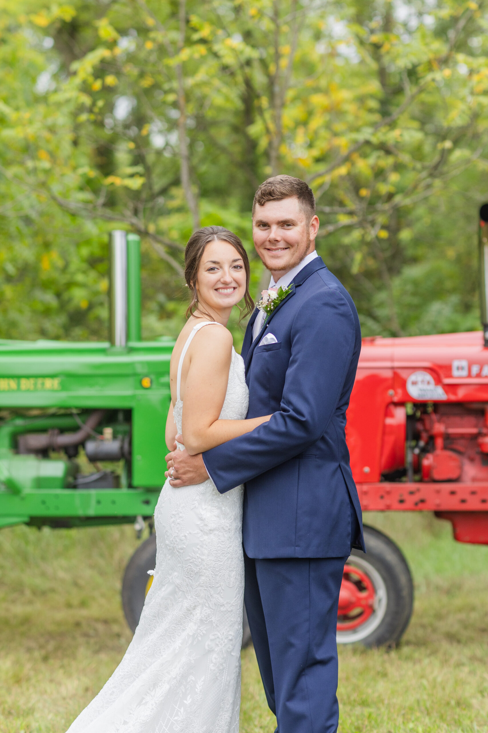 wedding couple posing in front of green and red tractors