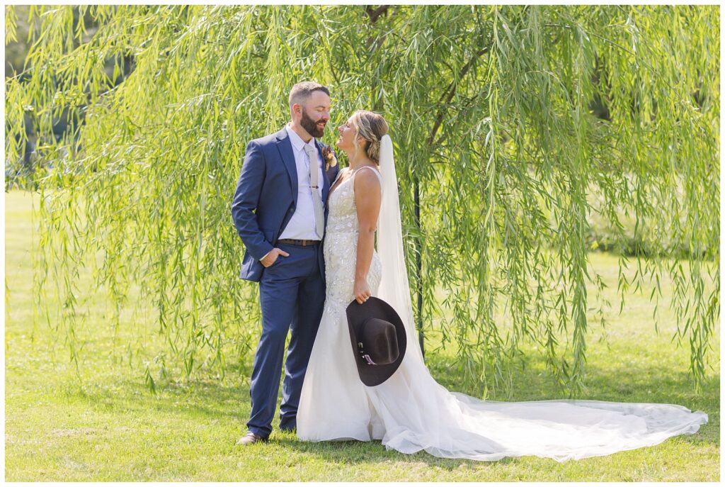wedding couple posing in front of a green willow tree in northwest Ohio