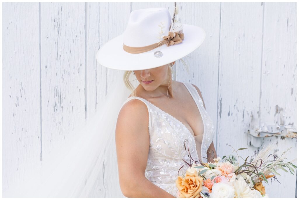 bride looking down while wearing an ivory cowboy hat and holding flowers 