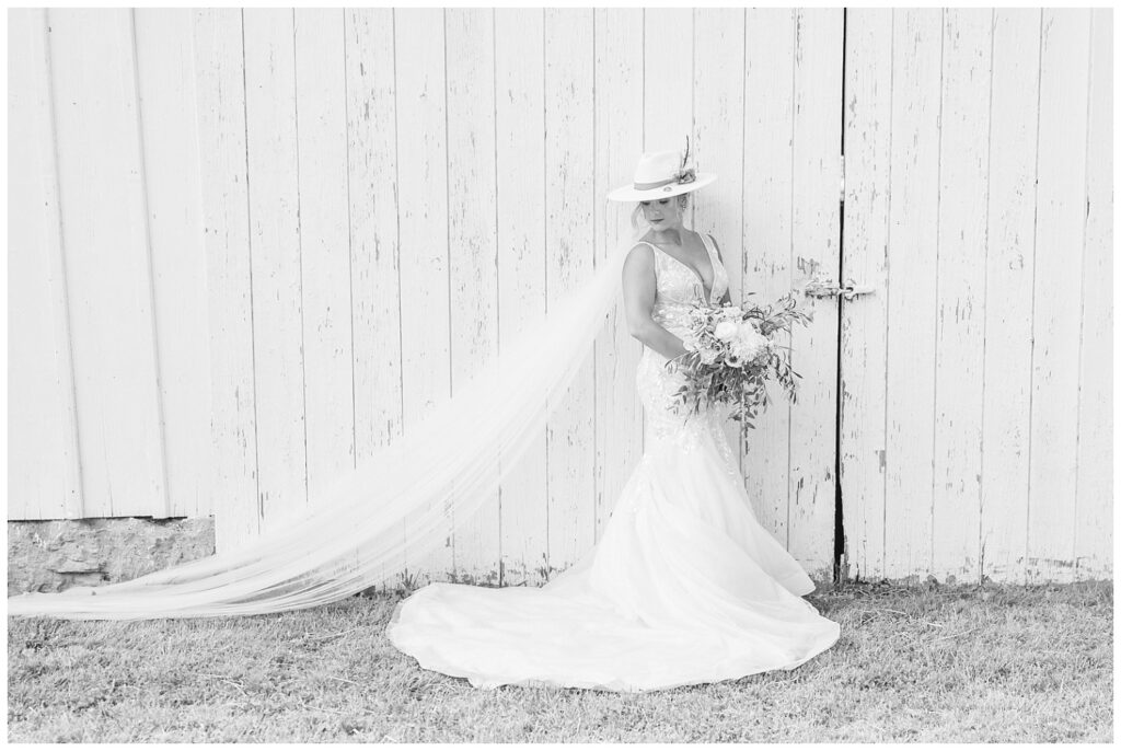 bride holding her bouquet and leaning against a white barn in Gibsonburg, Ohio