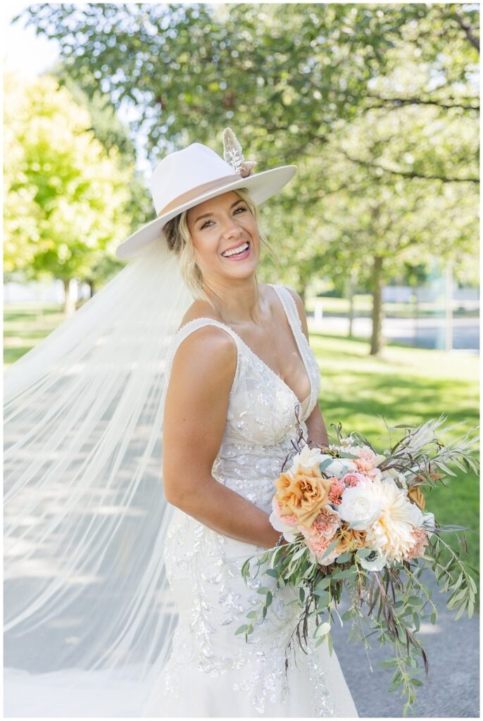 bride laughing and holding bouquet while standing on the bike trail 