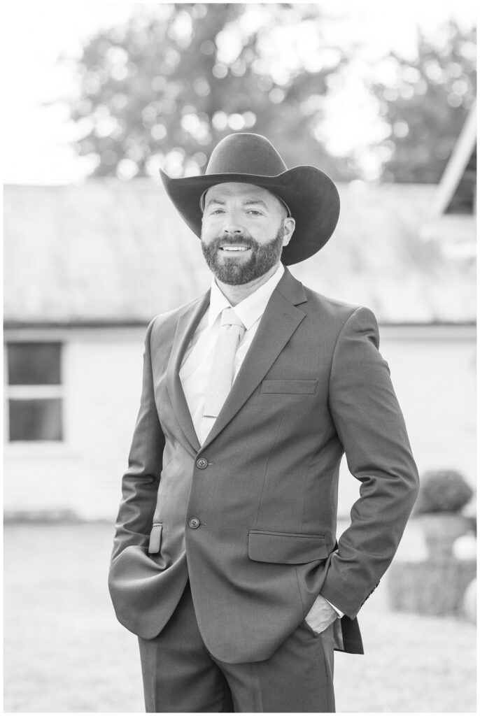 groom wearing a black cowboy hat with his hands in pockets 