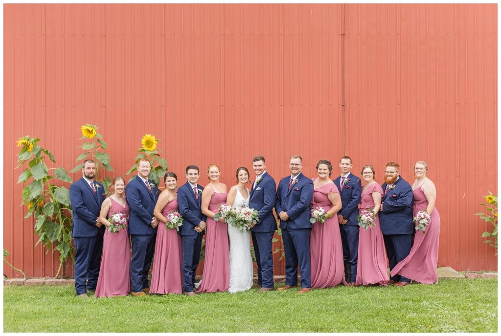 full wedding party posing in front of the bride and groom's red barn in Bowling Green, Ohio