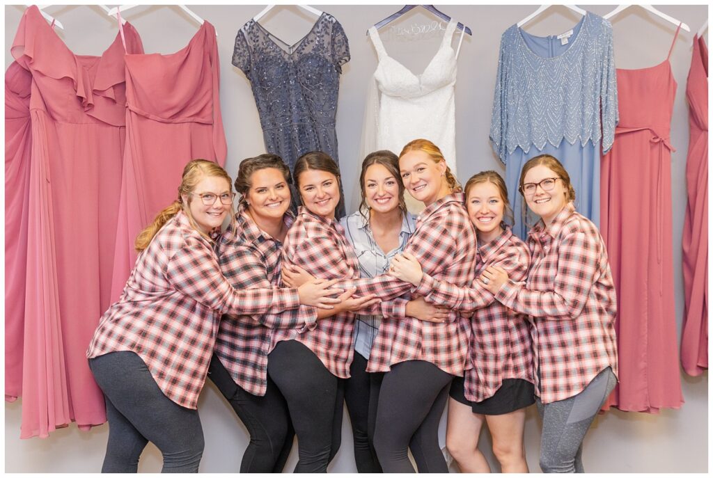 bridal party wearing plaid shirts standing in front of their dresses