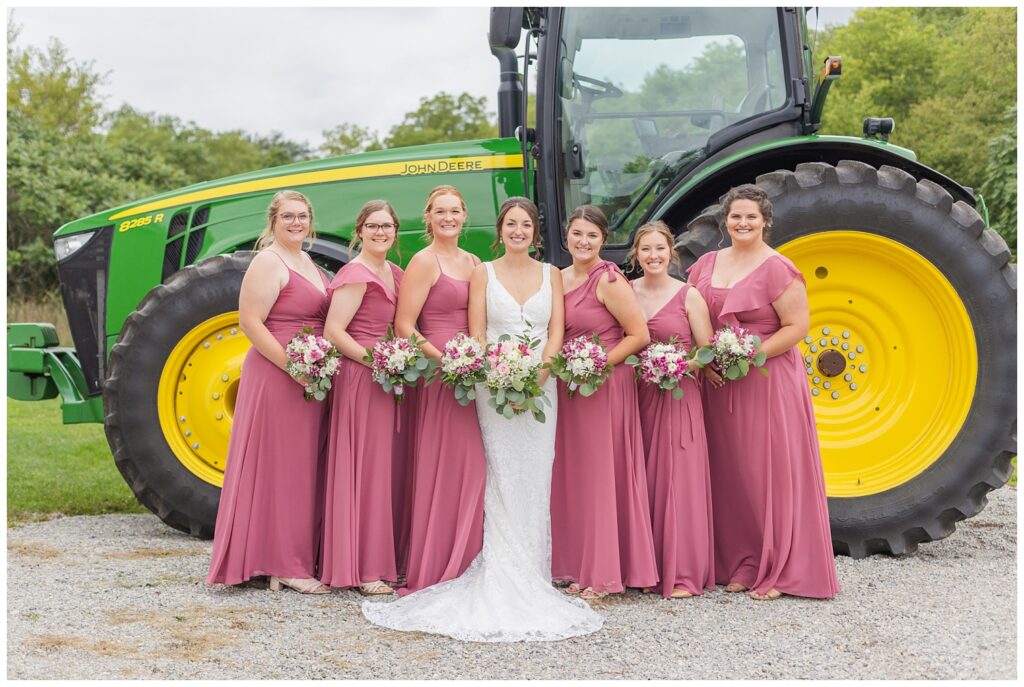 bridal party posing in front of the bride's green tractor